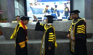 Pemindahan tali kuncir oleh Rektor UKSW Profesor Intiyas kepada Imelda Baransano dalam gelaran Yudisium Doktor Sosiologi Agama Fakultas Teologi UKSW, Jumat (20-06-2025).